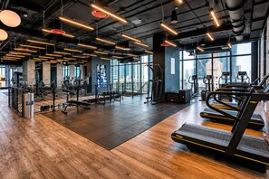 A modern gym with exercise equipment, large windows, and a high ceiling. - Stylish Ocean-View Condo in Downtown Miami (Miami)