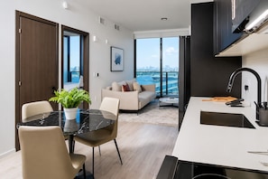 A modern kitchen with a black countertop, a sink, and a view of the city. - Stylish Ocean-View Condo in Downtown Miami (Miami)