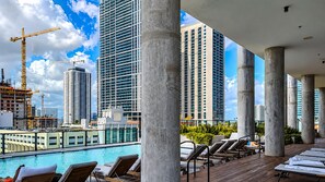 A rooftop pool area with lounge chairs, a swimming pool, and high-rise buildings in the background. - Stylish Ocean-View Condo in Downtown Miami (Miami)