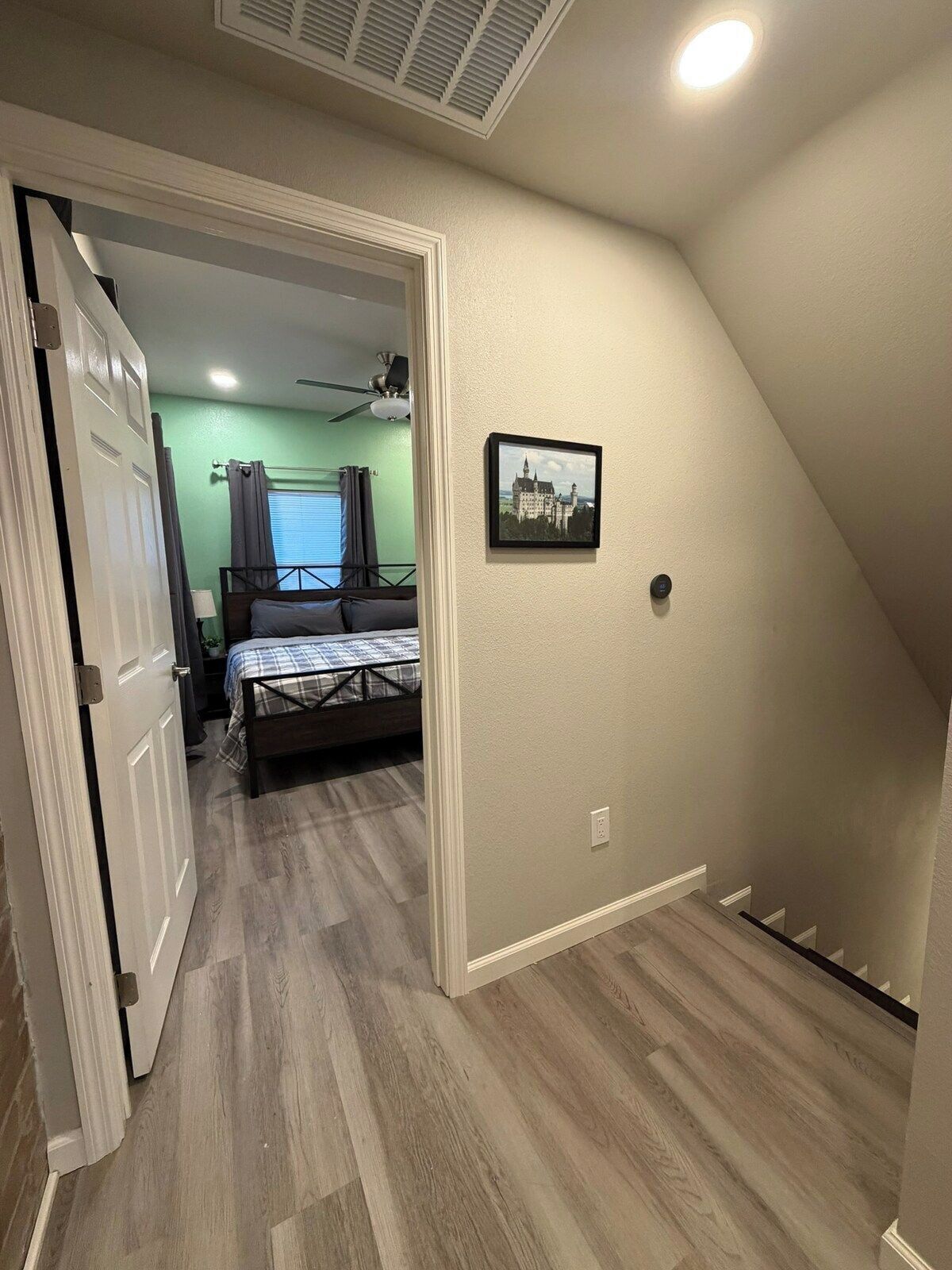 A room with a bed, a ceiling fan, and a picture on the wall.