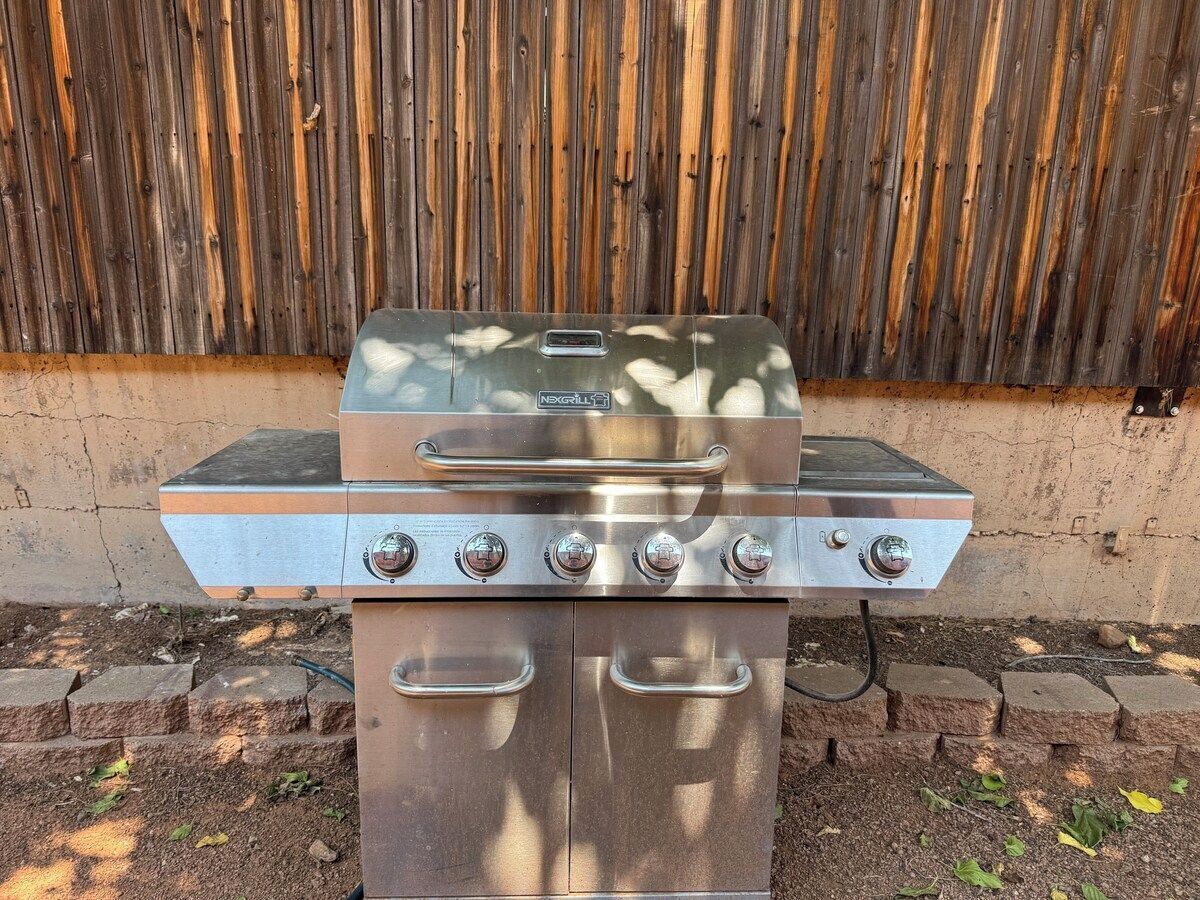 A stainless steel outdoor grill with four burners, a digital display, and a control panel.
