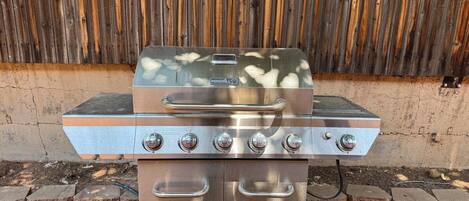 A stainless steel outdoor grill with four burners, a digital display, and a control panel.