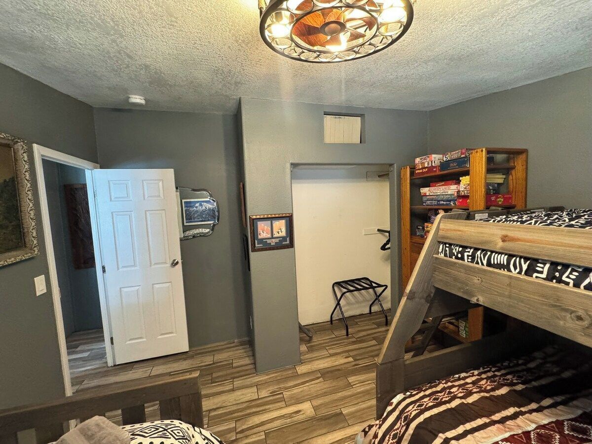 A room with a bunk bed, a door, a small table, and a wall-mounted TV.