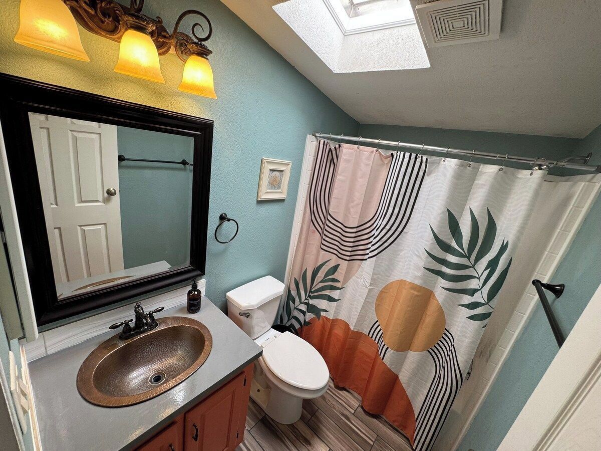 A bathroom with a sink, toilet, and shower curtain.