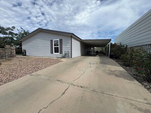 A residential property with a garage, a covered driveway, and a stone border.