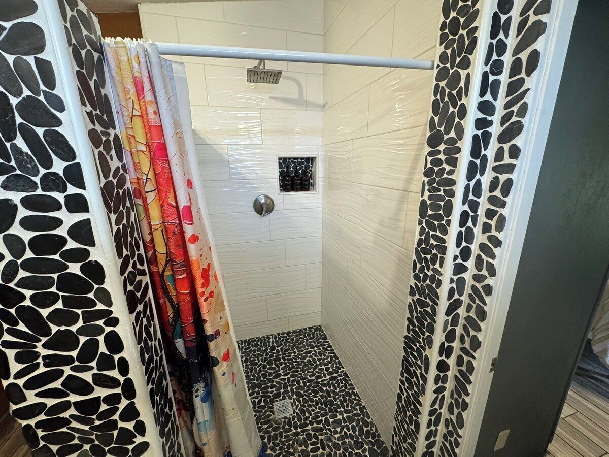 A shower with a tiled floor and a showerhead.