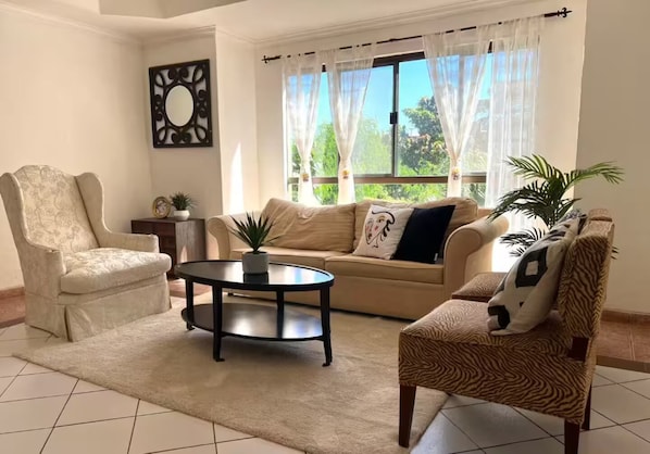 A living room with a sofa, two armchairs, a coffee table, and a decorative mirror. - Resort 5 Estrellas - Vista a Piscina & Jacuzzi (Santa Cruz de la Sierra)