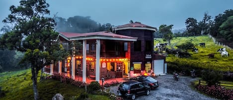 Un edificio de dos pisos con un letrero de restaurante, rodeado de un paisaje cubierto de césped y árboles.