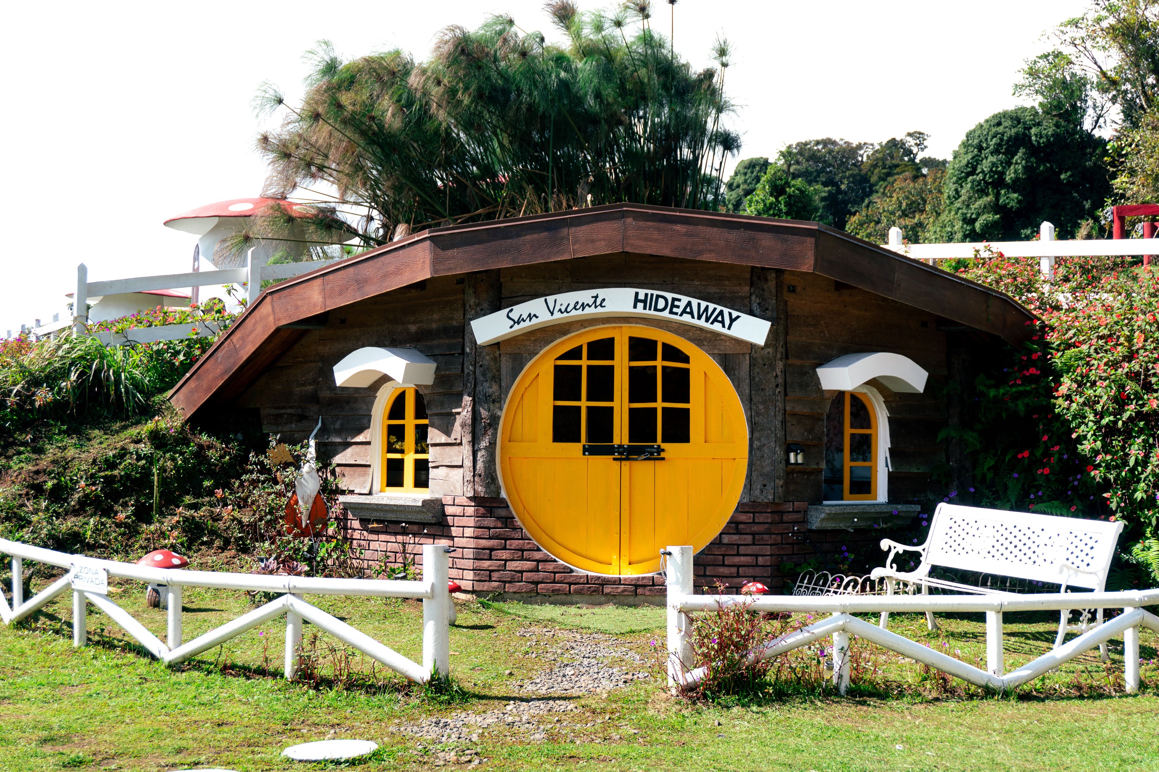 Un refuge rustique avec une porte jaune bien visible, une clôture blanche et un banc.