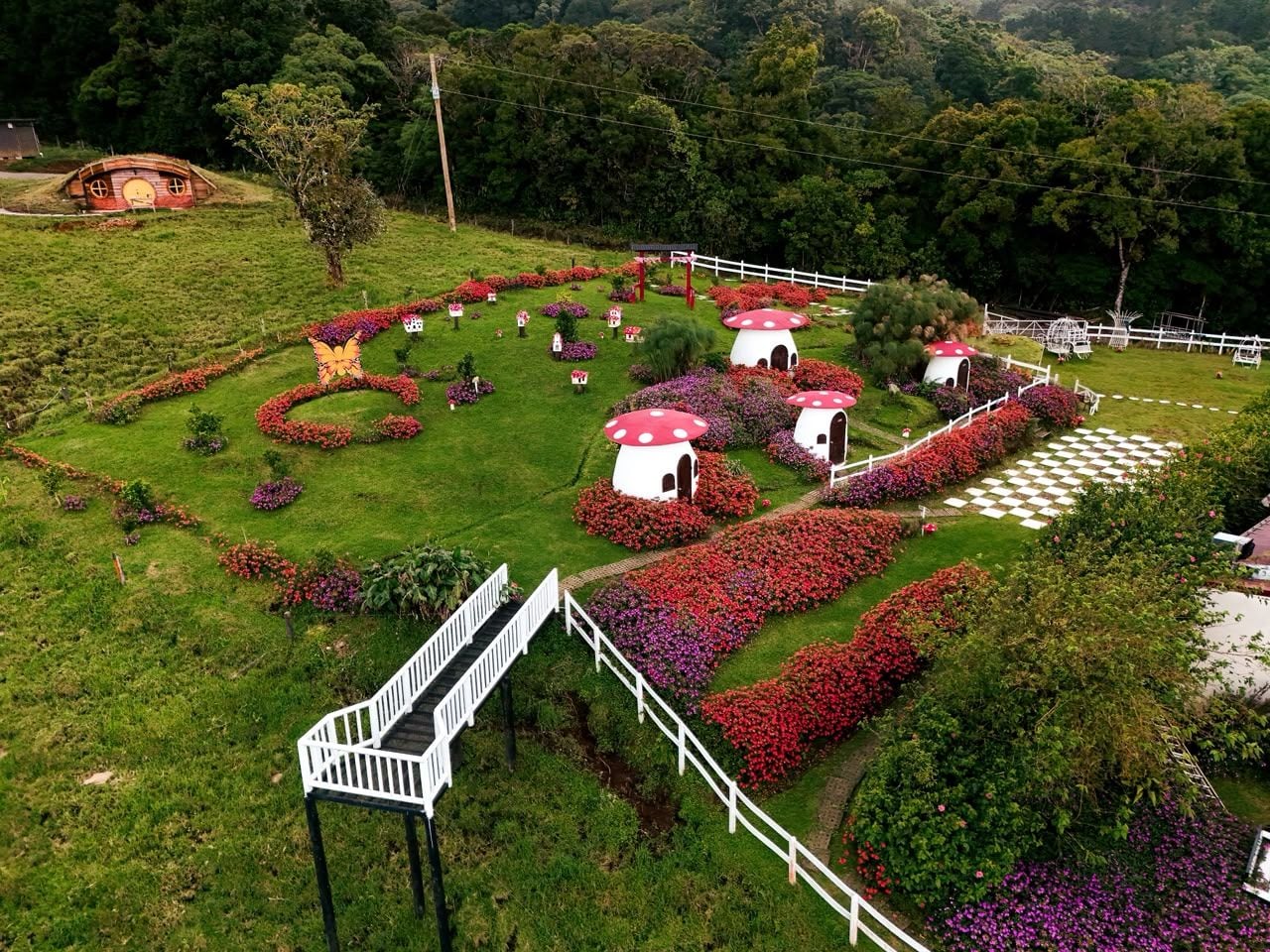 Un jardín con estructuras en forma de hongo, una cerca blanca y una escalera.
