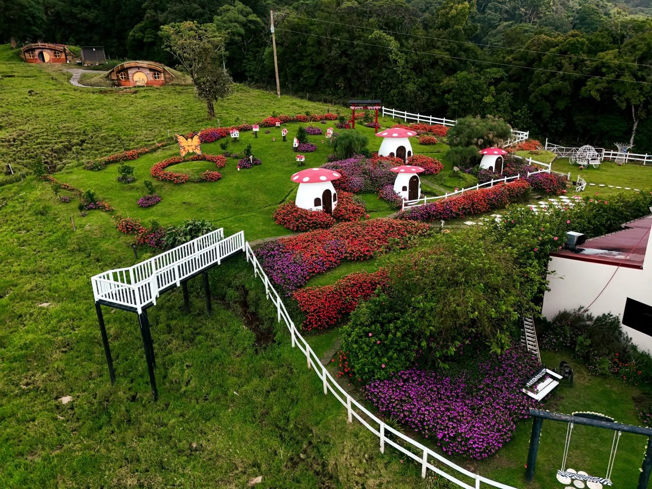 A garden with mushroom-shaped structures, a white fence, and a pathway.