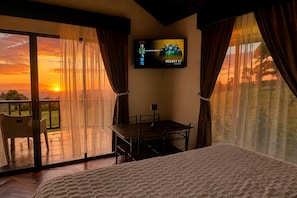 A bedroom with a bed, a TV mounted on the wall, a table, and chairs.