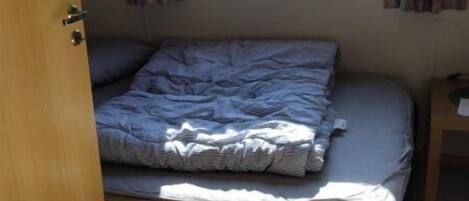 A small bedroom with a single bed, a window with curtains, and a door.