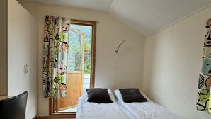 Un dormitorio con una cama, una silla, un ventanal y una lámpara en el techo.