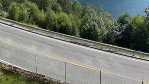 A coastal road with a view of a body of water and mountains in the distance.