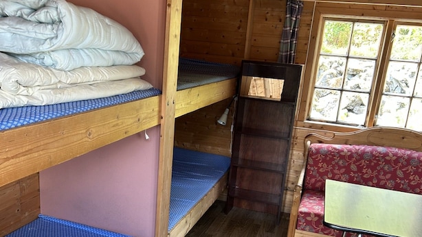 A cabin interior with bunk beds, a small table, and a bench.
