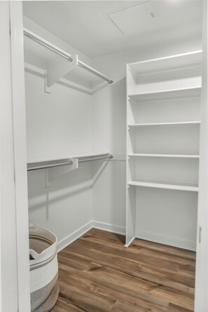 Ein begehbarer Kleiderschrank mit weißen Regalen und Holzboden.