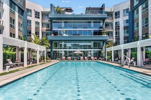 Et moderne hotel med central swimmingpool, loungeområder og en bygning med flere etager og altaner.