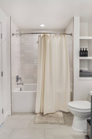 Et moderne badeværelse med badekar, toilet og bruseforhæng.