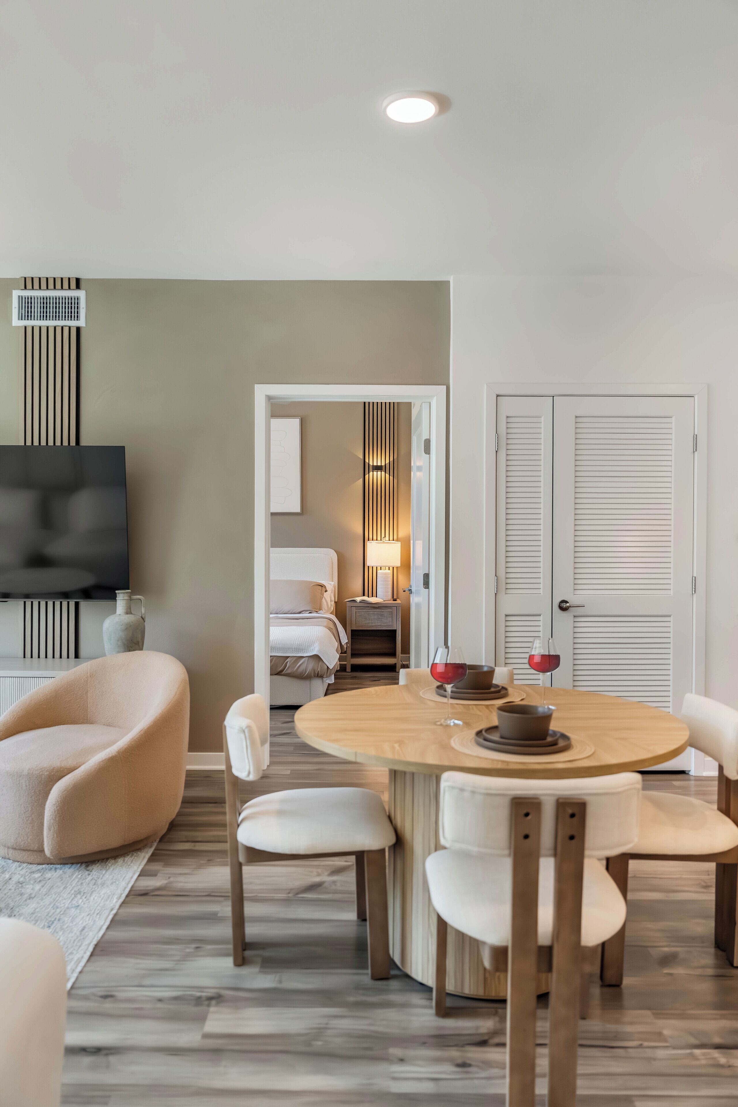 Ein modernes Wohnzimmer mit einem runden Esstisch, weißen Stühlen, einem Flachbildfernseher und einem Kamin.
