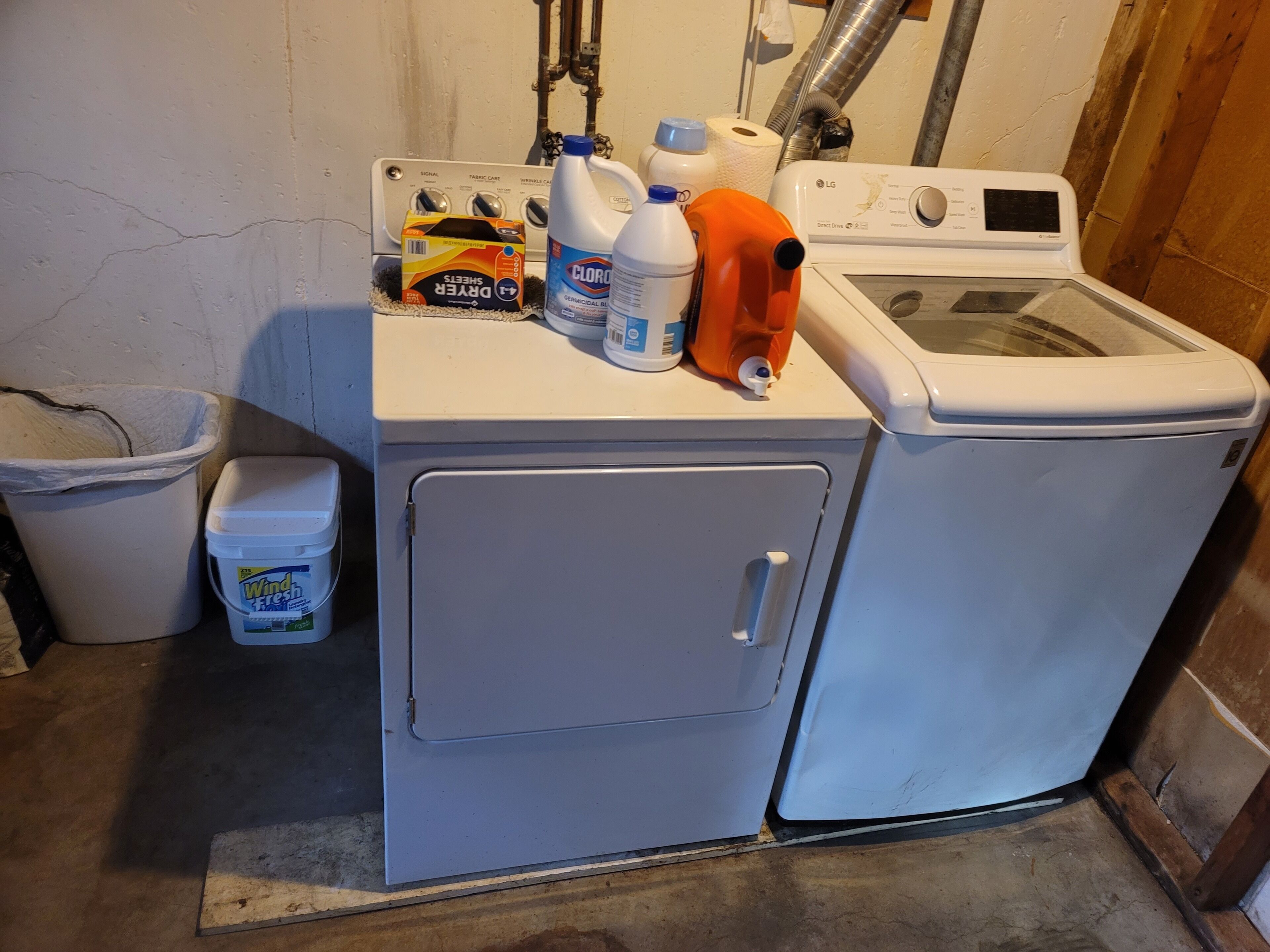 A laundry area with a washing machine, a dryer, and various cleaning supplies.