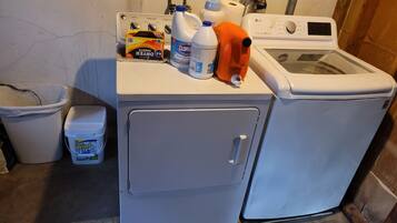 A laundry area with a washing machine, a dryer, and various cleaning supplies.