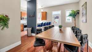 Una cocina moderna con armarios de madera, un comedor con una mesa grande y sillas, y una planta en maceta.