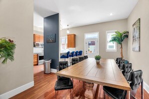 Eine moderne Küche mit Holzausstattung, ein Essbereich mit großem Tisch und Stühlen sowie ein Blumentopf.