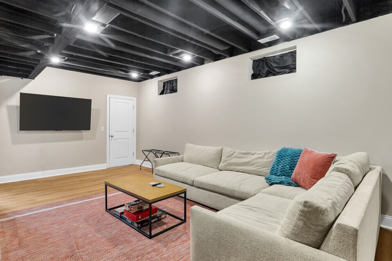Ein modernes Wohnzimmer mit einem Ecksofa, einem Couchtisch und einem flachbildfernseher an der Wand.