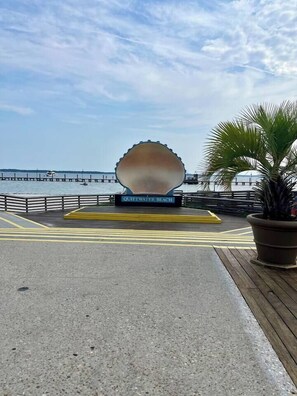 A waterfront promenade with a large shell sculpture, a sign reading 'Quiet Water Beach,' and a palm tree. - Gulf Breeze- 10 min to beaches, 4bed, 2.5bath (Gulf Breeze)