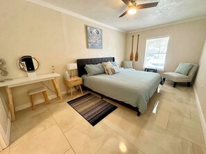 Une chambre à coucher comprenant un lit, une table de chevet, une chaise et un bureau avec un miroir.