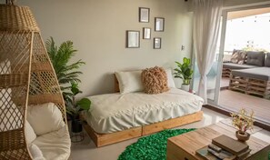 Ein Schlafzimmer mit einem hölzernen Plattformbett, einem Hängekorbstuhl und einem grünen Teppich.