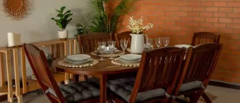 A dining area with a brick wall, wooden table, and chairs.