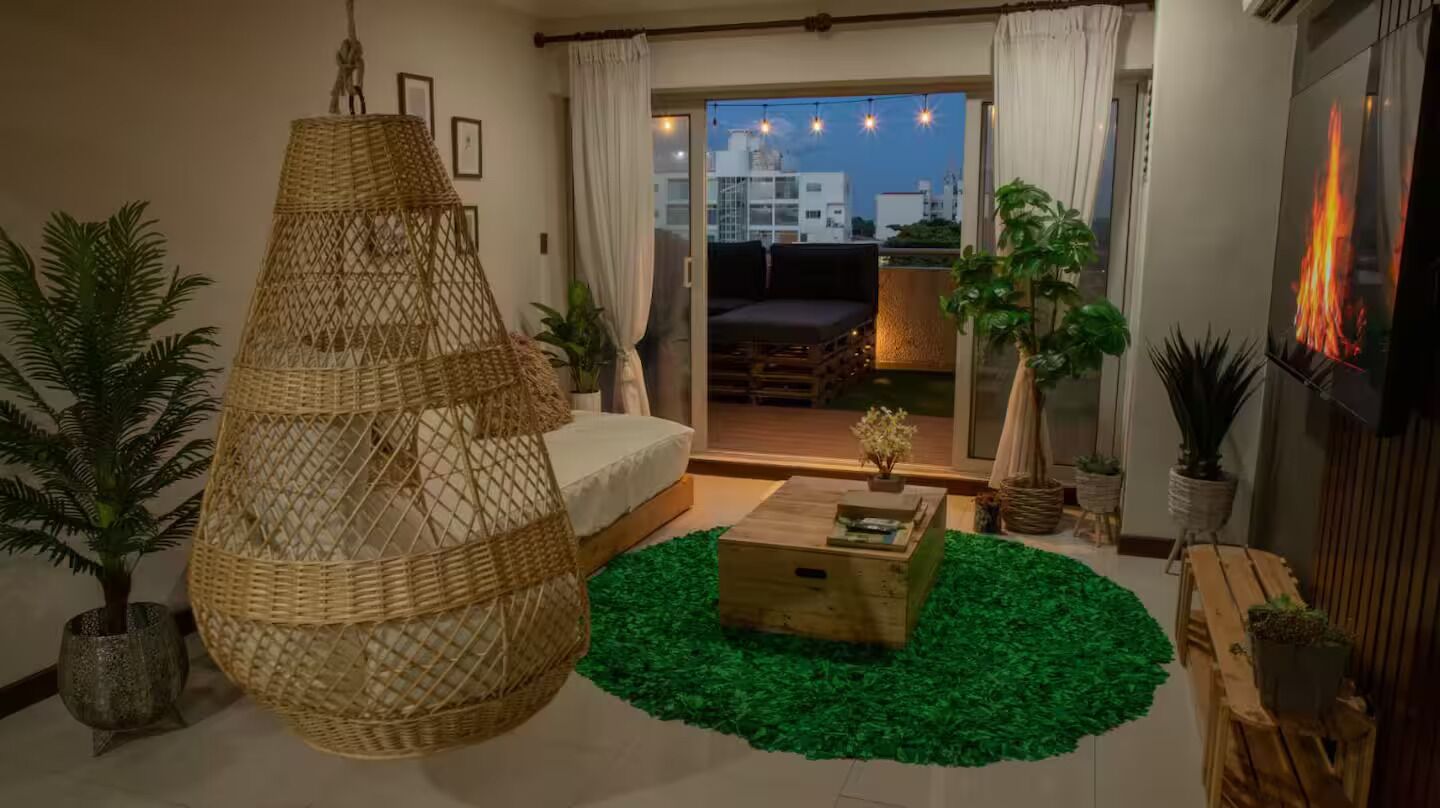A cozy living room with a large woven chair, a wooden coffee table, and a green rug.