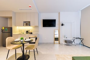 A modern kitchen with a dining area, a flat-screen TV mounted on the wall, and a small ironing station. - Olma (San Pedro Garza García)