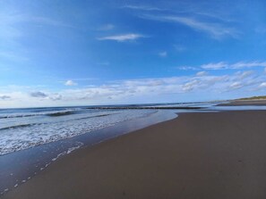 A beach with a clear sky and calm sea. - Cozy bungalow near the beach (Julianadorp)
