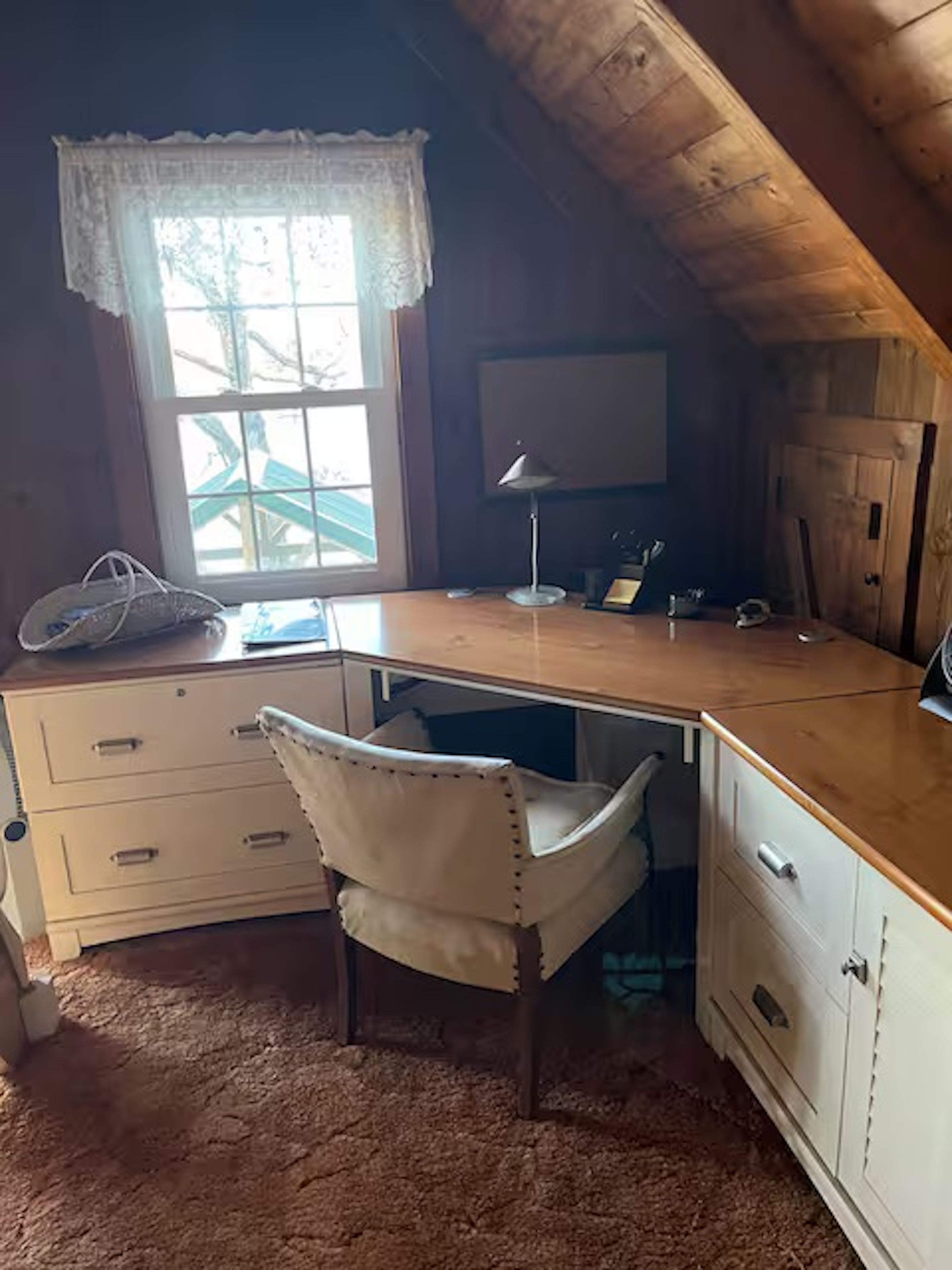 A room with a desk, chair, and a window with a view.