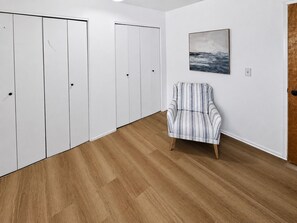 Ein Zimmer mit Holzboden, einem gestreiften Sessel und weißen Türen.