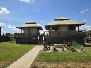 A two-story house with a deck, a covered outdoor seating area, and a pathway leading to the entrance.