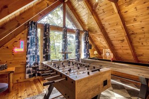 Ein Spielzimmer mit Focaccia-Tisch, Holzwänden und großen Fenstern.