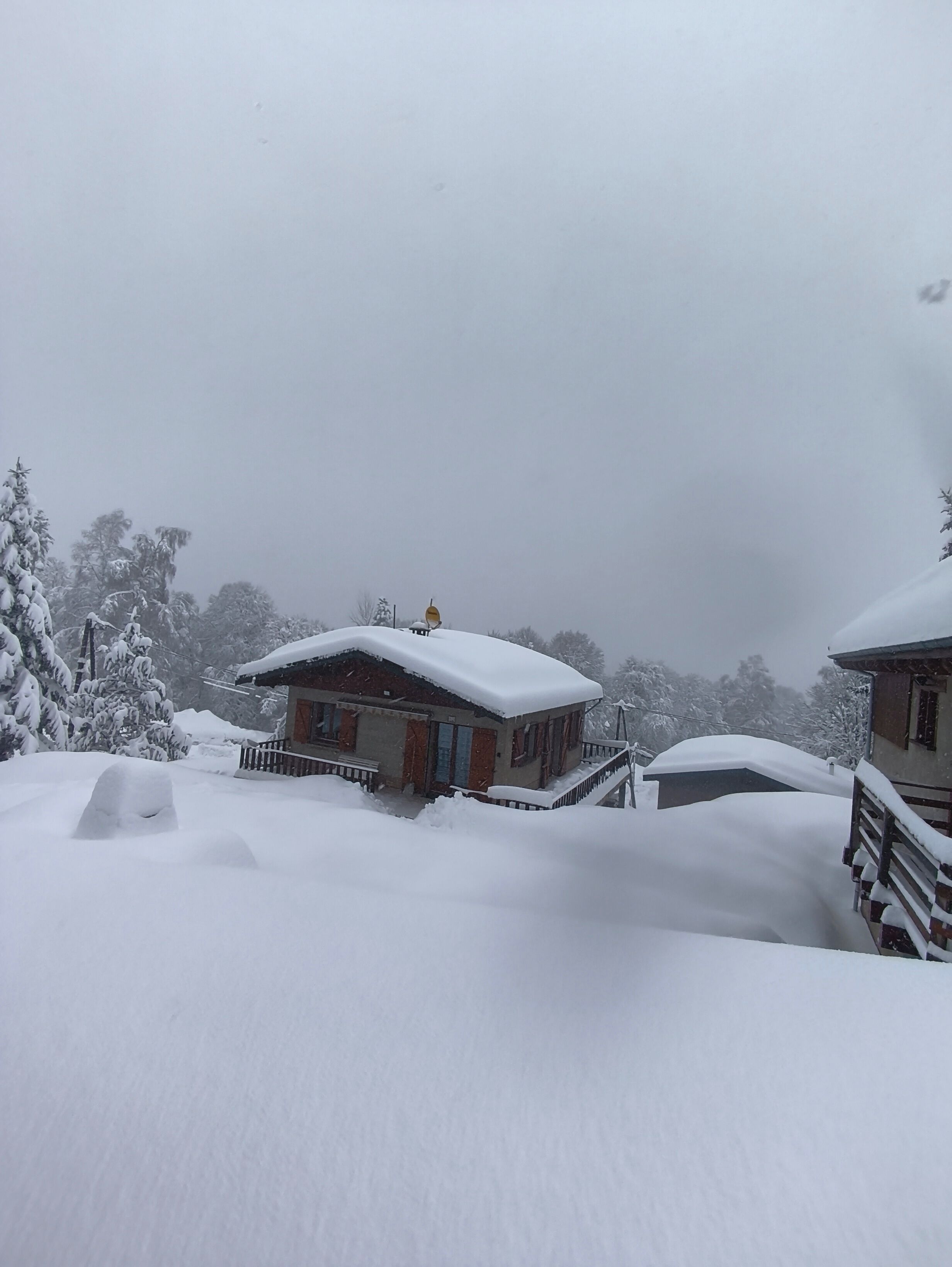 Un bâtiment recouvert de neige, doté d’un porche et d’un toit également enneigé.
