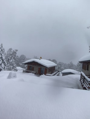 A snow-covered building with a porch and a snow-covered roof.