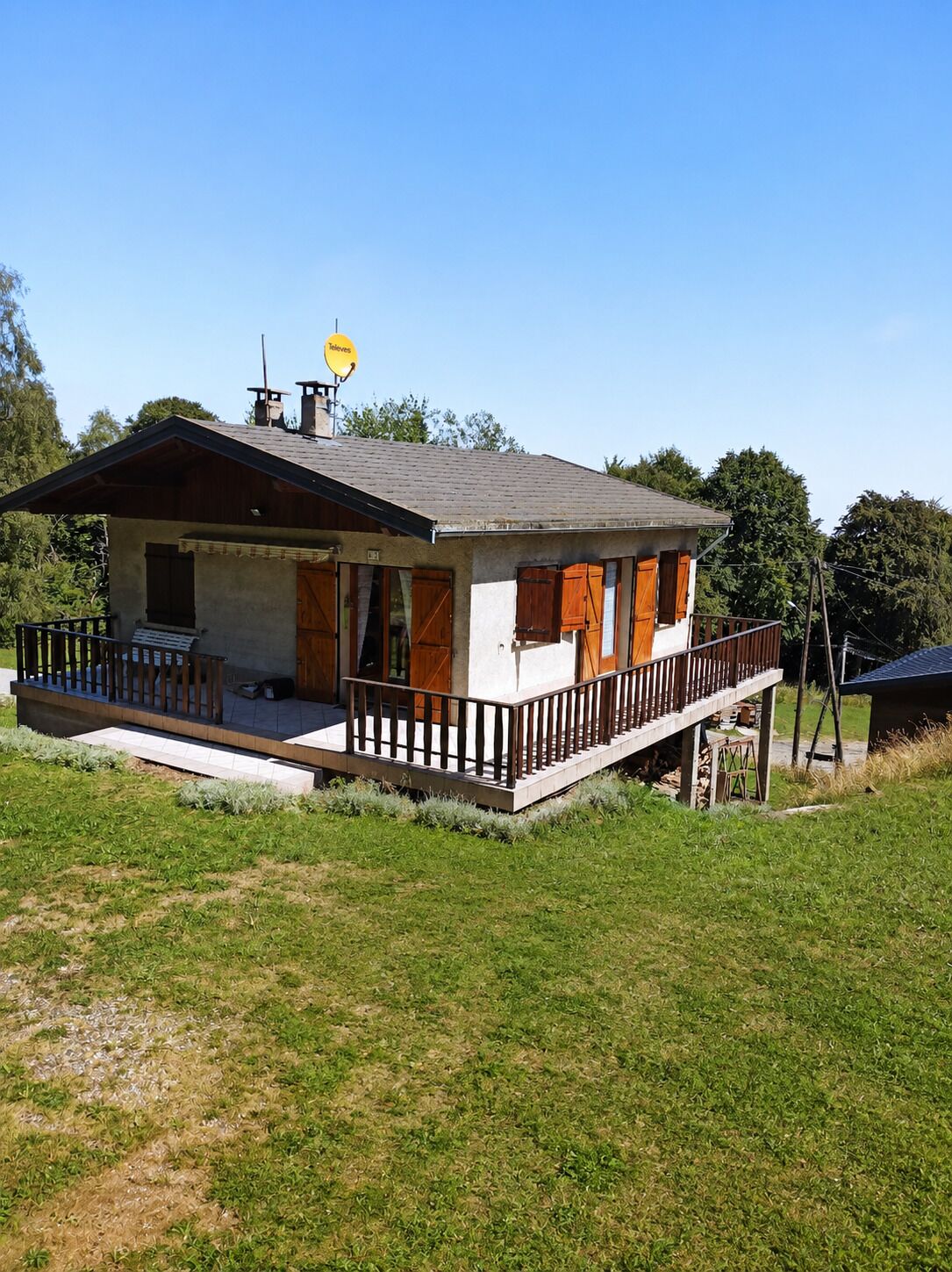 Une maison de plain-pied avec un porche, une antenne parabolique et une petite terrasse.