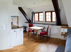 Una cocina funcional con comedor, piso de madera y ventana con cortinas.