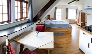 Habitació petita amb llit, taula i zona de cuina.