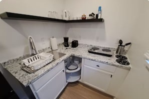 Une cuisine compacte dotée d’un plan de travail en granit, d’une machine à café, d’une bouilloire et d’un grille-pain.