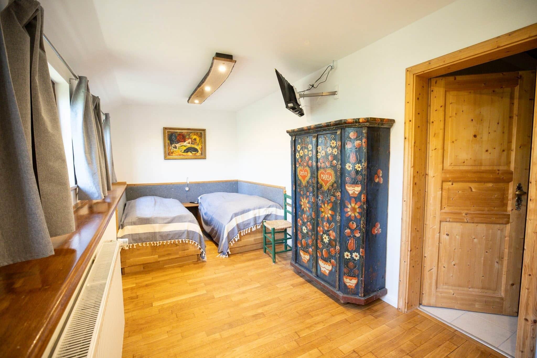 Un dormitorio con dos camas, un armario de madera y una puerta.