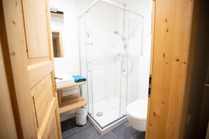 Ein Badezimmer mit Duschkabine, Toilette und einem Holzwaschtisch mit Handtuch.