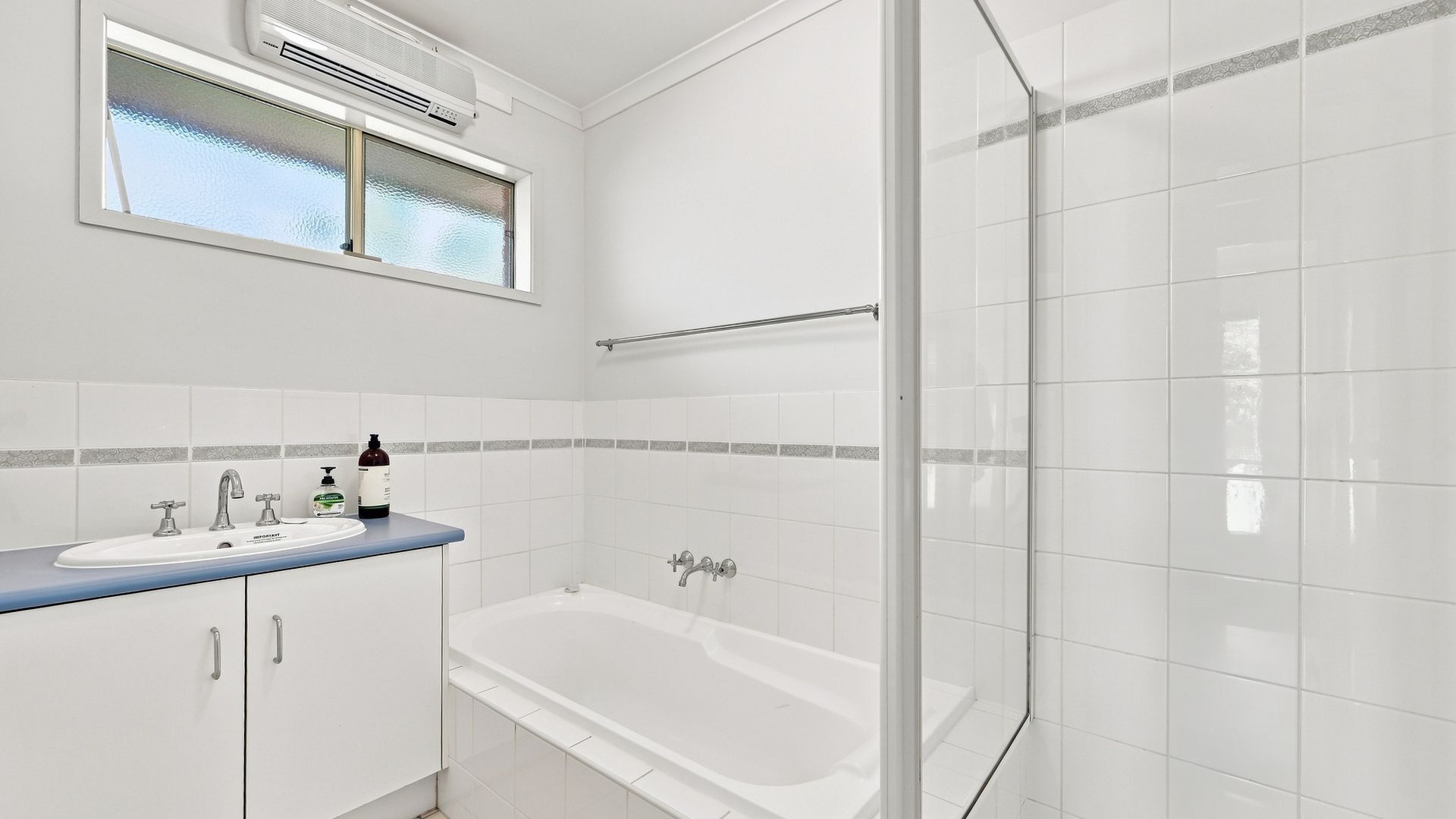 Un baño moderno con bañera, lavamanos con encimera azul y cabina de ducha de cristal.