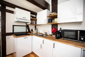 A compact kitchen with white cabinets, a wooden countertop, a built-in microwave, a coffee maker, and a kettle. - Tüschenbeker Mill - Mühlengarten Apartment (4–5 people) (Groß Sarau)